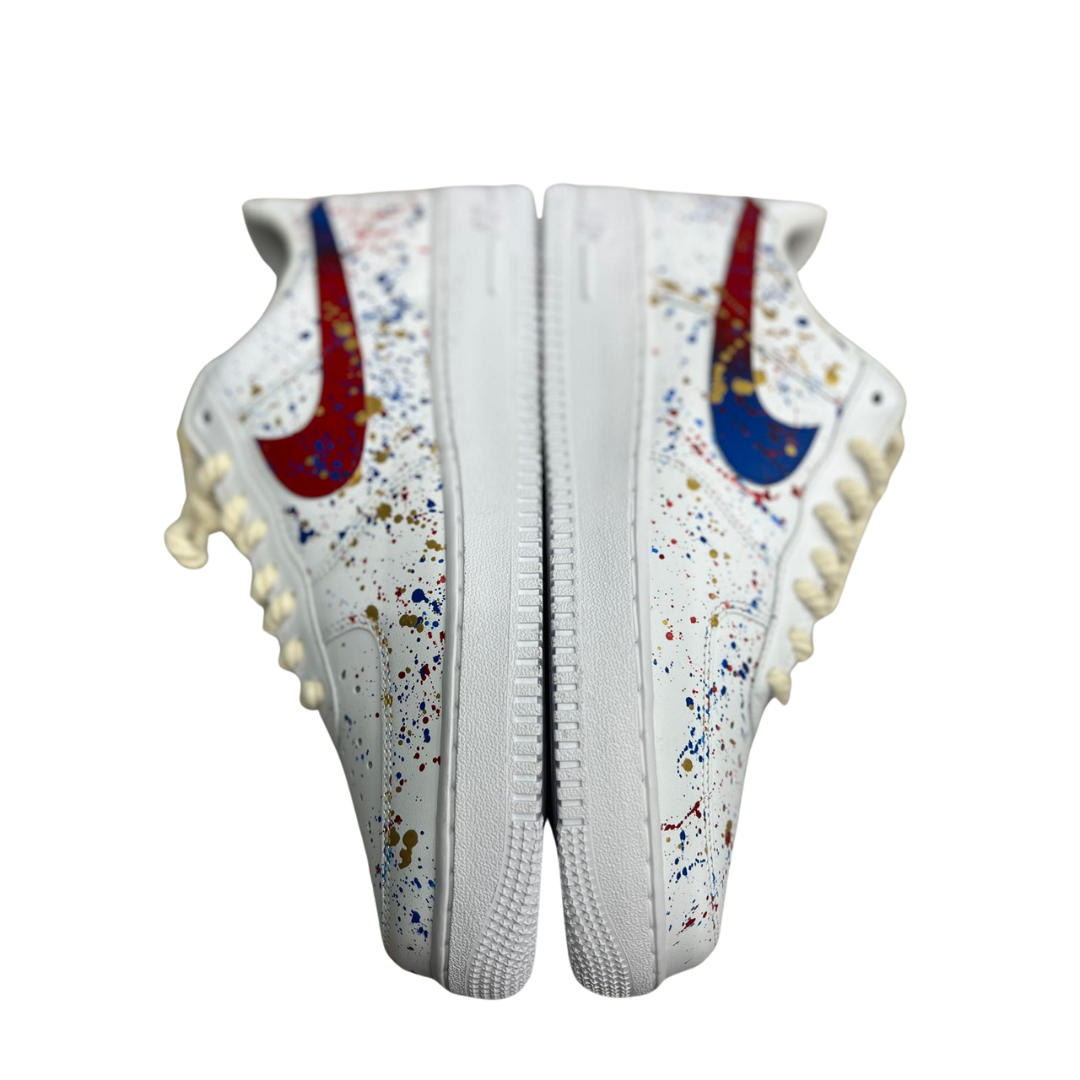 a pair of white shoes with colorful drops on it