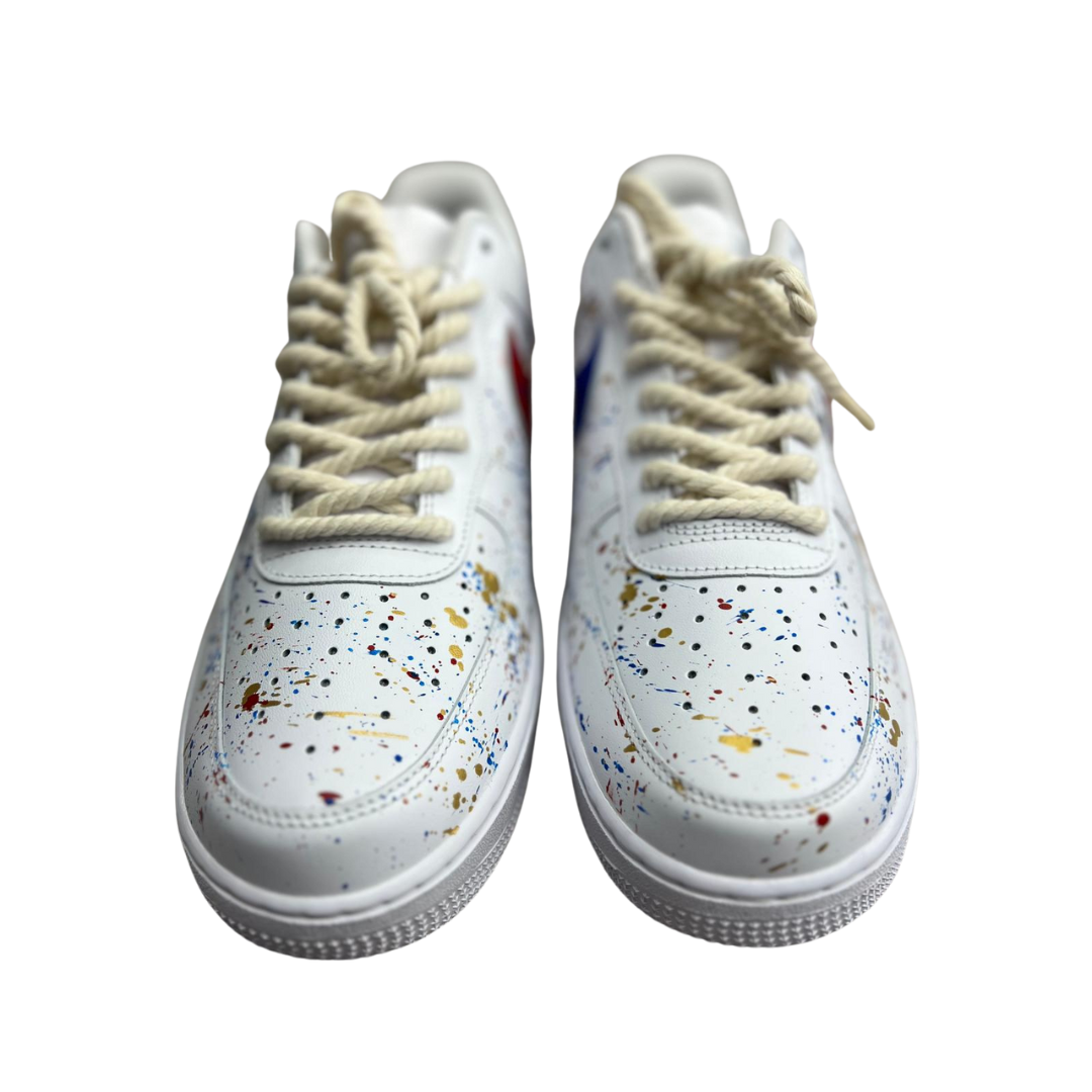 a pair of white shoes with splatter paint drops
