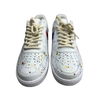 a pair of white shoes with splatter paint drops