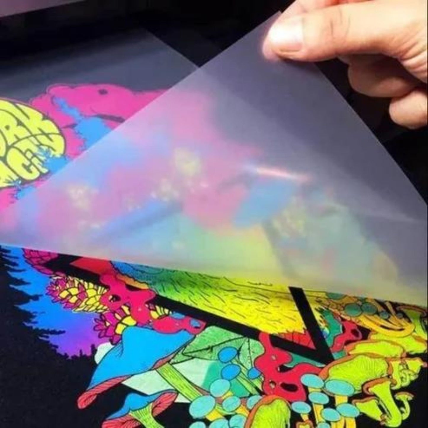 A person lifts a semi-transparent sheet to reveal a multicolored, psychedelic design featuring various abstract shapes and vibrant colors