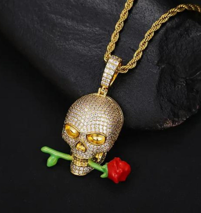 a gold necklace with a skull and a rose